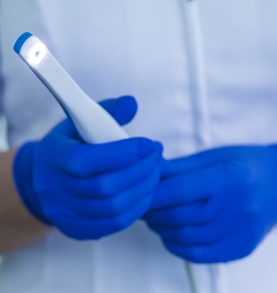 Dental professional holding a thin white intraoral camera
