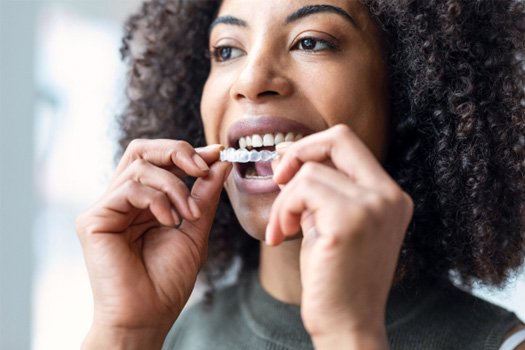 A woman putting on an Invisalign aligner near Santa Clara