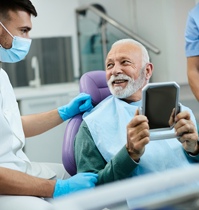 Young man in dental chair talking to dental team member