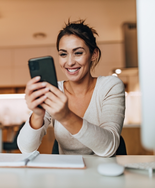Brunette woman in a white blouse smiling after cosmetic dentistry in San Jose