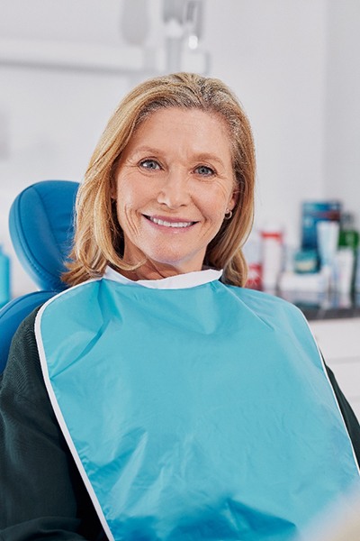 Mature blonde woman sitting in dental chair and smiling