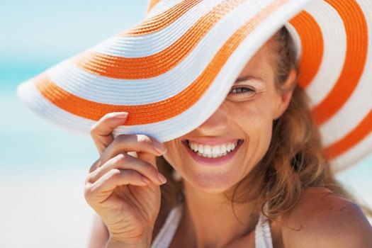 Woman in floppy beach hat smiling brightly