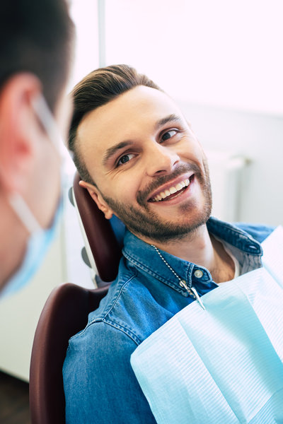Pretty face mimic and a white smile of a nice man in a dental chair after getting a doctor’s treatment in a professional clinic.