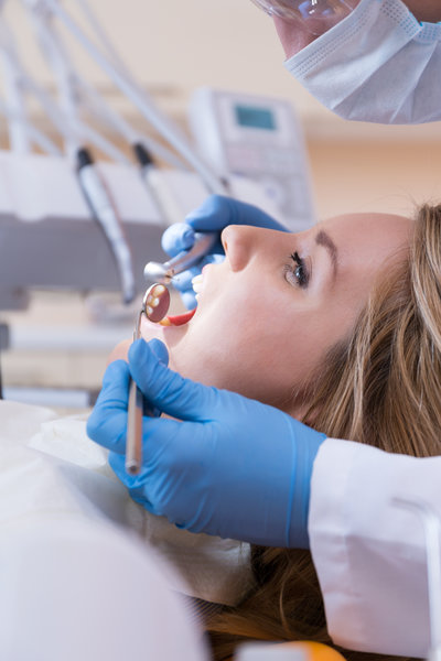 Dentist using dental drill and mouth mirror